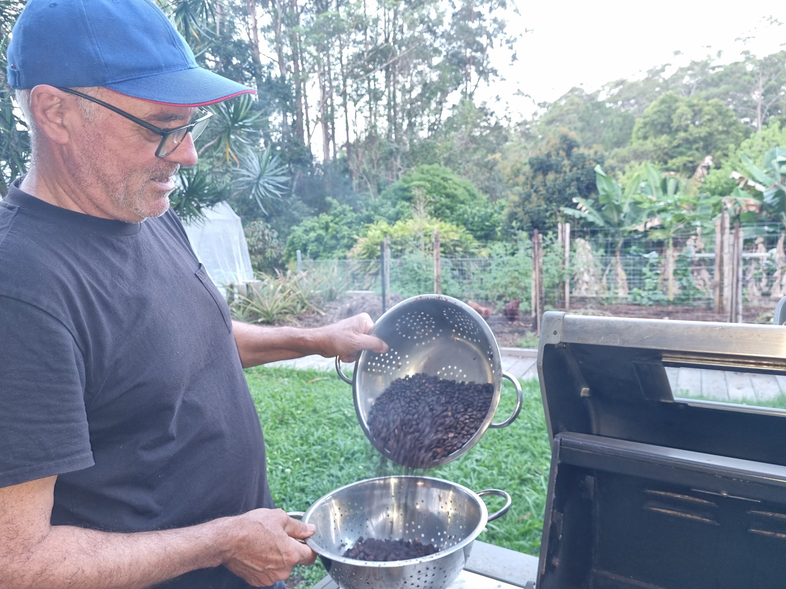 Pouring hot roasted beans from sieve to sieve to cool them down.
